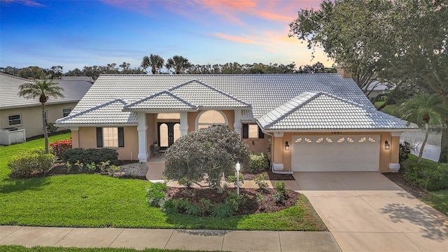view of front of property featuring a garage, a front lawn, stucco siding, and a tile roof