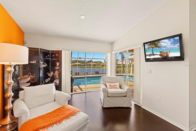 living area with a textured ceiling, vaulted ceiling, baseboards, and hardwood / wood-style flooring