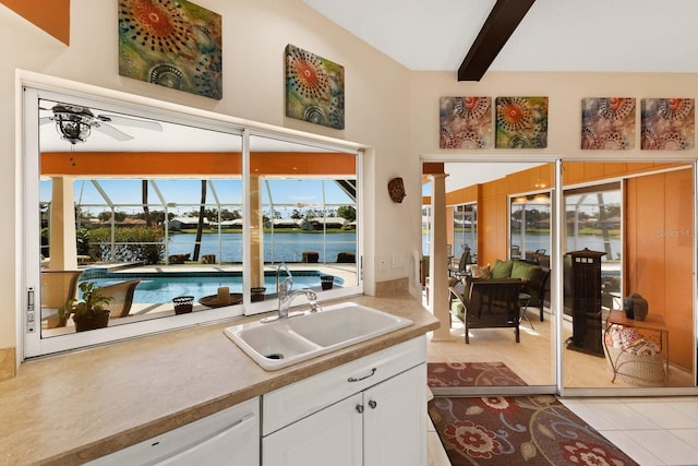 kitchen featuring white cabinets, a sink, a ceiling fan, light tile patterned floors, and a water view