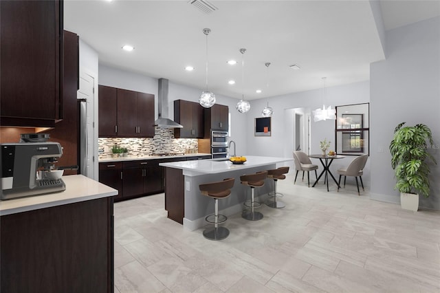 8229 Grande Shores Dr, Sarasota, FL 34240 - kitchen with wall chimney exhaust hood, a breakfast bar, a sink, light countertops, and tasteful backsplash