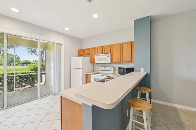 2353 Rosewood Ln, North Port, FL 34289 - kitchen featuring white appliances, light countertops, light tile patterned flooring, a breakfast bar, and a sink