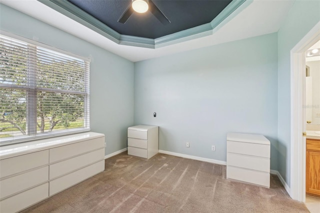 2353 Rosewood Ln, North Port, FL 34289 - unfurnished bedroom featuring a tray ceiling, light carpet, connected bathroom, baseboards, and ceiling fan