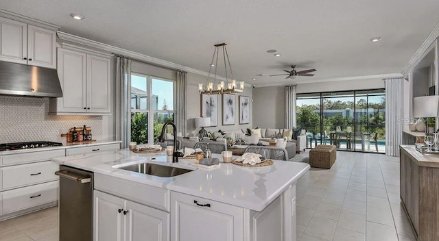kitchen featuring a sink, under cabinet range hood, tasteful backsplash, crown molding, and gas cooktop