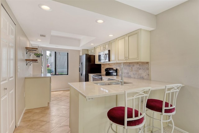 7876 Eagle Creek Dr, Sarasota, FL 34243 - kitchen with cream cabinets, black appliances, baseboards, backsplash, and light tile patterned floors
