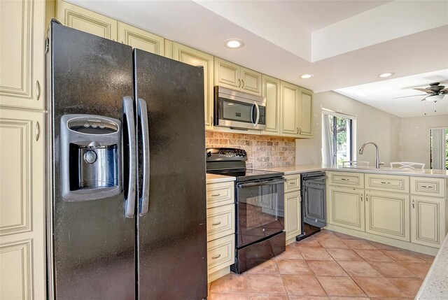 7876 Eagle Creek Dr, Sarasota, FL 34243 - kitchen featuring cream cabinetry, black appliances, recessed lighting, decorative backsplash, and a sink