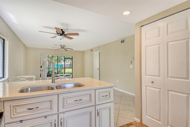 7876 Eagle Creek Dr, Sarasota, FL 34243 - kitchen featuring a sink, light tile patterned flooring, a ceiling fan, light stone countertops, and baseboards