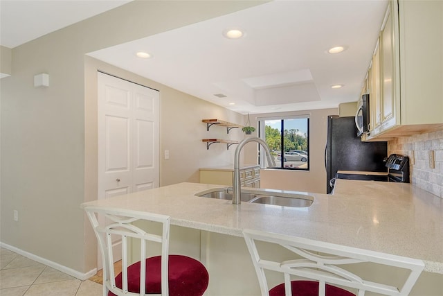 7876 Eagle Creek Dr, Sarasota, FL 34243 - kitchen with a peninsula, a sink, stove, a breakfast bar, and light stone counters