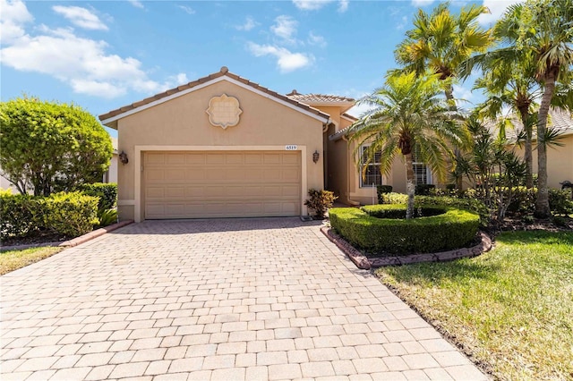 6519 43rd Ct E, Sarasota, FL 34243 - mediterranean / spanish-style house with a garage, stucco siding, a front lawn, and decorative driveway