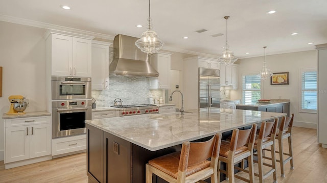 345 Madison Dr, Sarasota, FL 34236 - kitchen with wall chimney range hood, appliances with stainless steel finishes, decorative backsplash, and light wood-type flooring