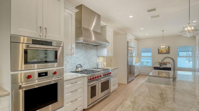 345 Madison Dr, Sarasota, FL 34236 - kitchen with wall chimney range hood, light stone counters, a sink, light wood-style flooring, and premium appliances