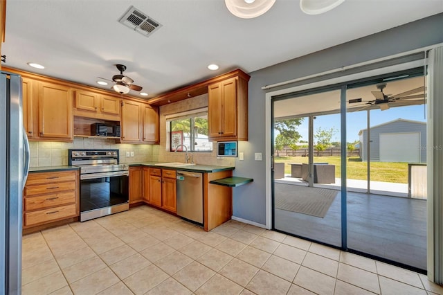 kitchen featuring visible vents, a ceiling fan, appliances with stainless steel finishes, and decorative backsplash