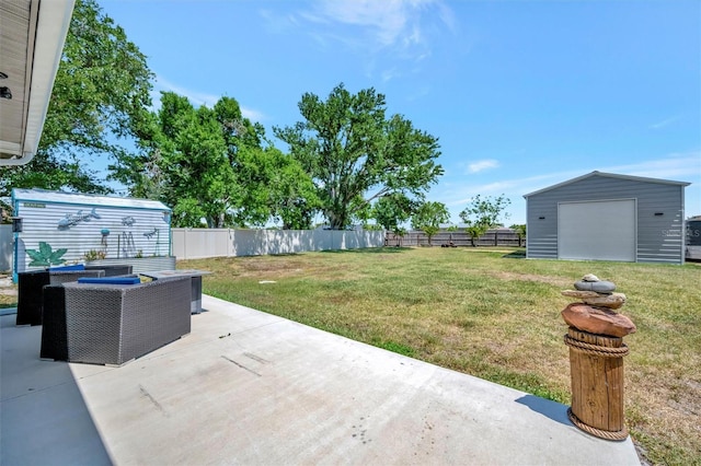 view of yard featuring fence, an outdoor structure, a detached garage, and a patio