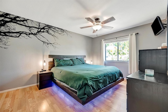 bedroom with ceiling fan, light wood-style flooring, and baseboards