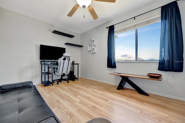 exercise area with wood finished floors, ceiling fan, and baseboards