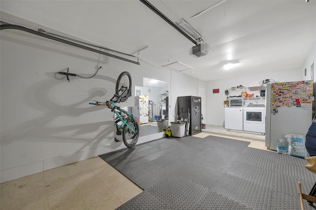 garage with a garage door opener, fridge, washing machine and clothes dryer, and freestanding refrigerator