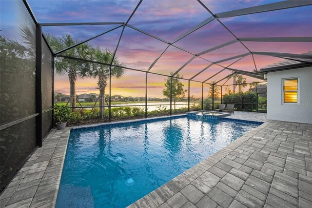 view of swimming pool featuring glass enclosure, a pool with connected hot tub, and a patio area