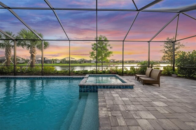 view of pool with a patio, a water view, a pool with connected hot tub, and glass enclosure