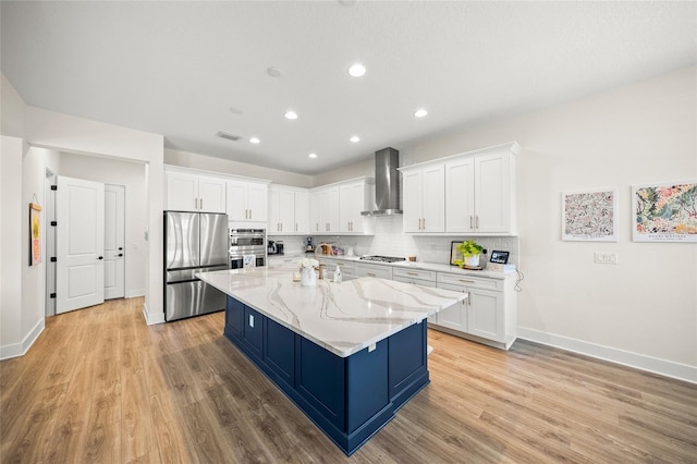 kitchen with wall chimney range hood, appliances with stainless steel finishes, baseboards, and white cabinetry