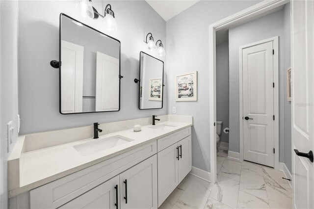 full bathroom with a sink, baseboards, toilet, and marble finish floor