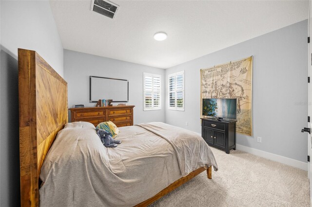 bedroom featuring visible vents, baseboards, and light colored carpet