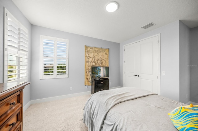 carpeted bedroom featuring baseboards, visible vents, and a closet
