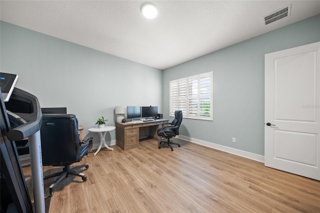 office space featuring visible vents, light wood finished floors, and baseboards