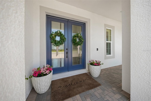 view of exterior entry featuring stucco siding and french doors