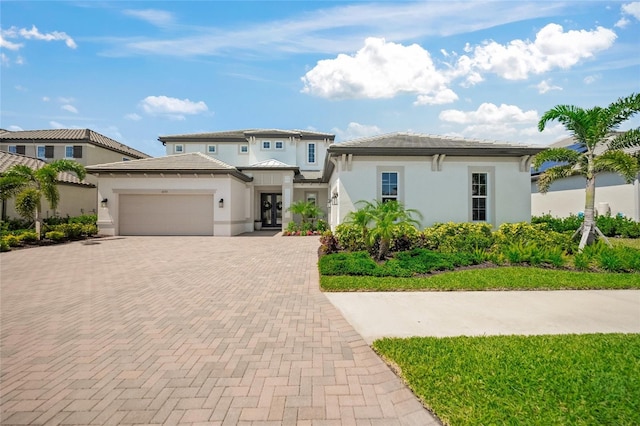 prairie-style house featuring stucco siding, decorative driveway, and a garage