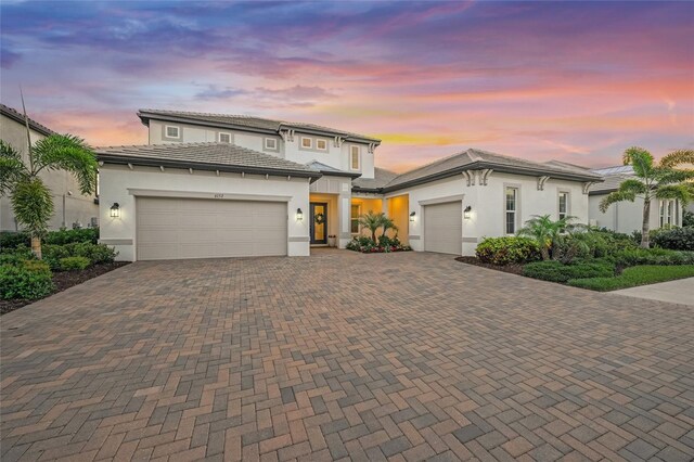 view of front facade with an attached garage, stucco siding, and decorative driveway