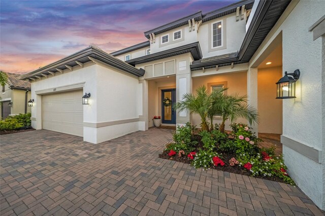 view of front of property featuring a garage, stucco siding, and decorative driveway