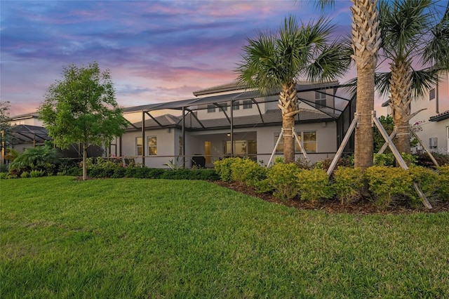 back of property featuring glass enclosure, stucco siding, and a yard