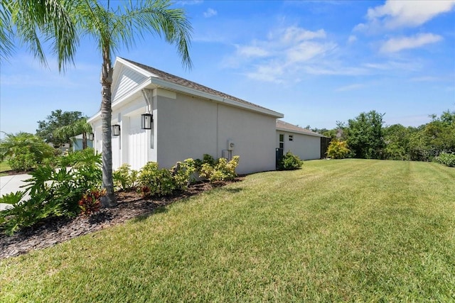 view of side of home with a lawn and stucco siding