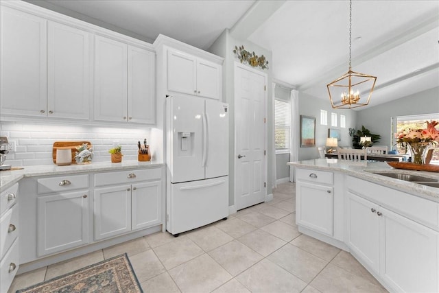 kitchen with decorative backsplash, white refrigerator with ice dispenser, a sink, light tile patterned floors, and a notable chandelier