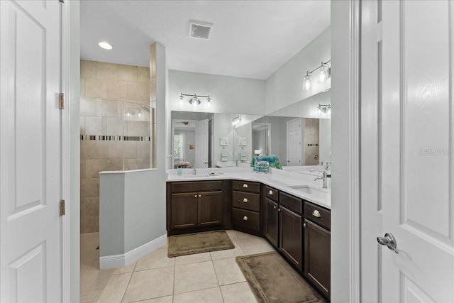 full bath featuring visible vents, a sink, a walk in shower, and tile patterned floors