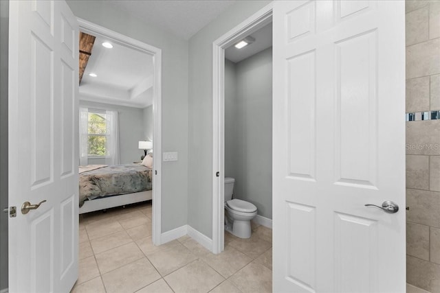 bathroom featuring baseboards, tile patterned flooring, ensuite bathroom, and toilet