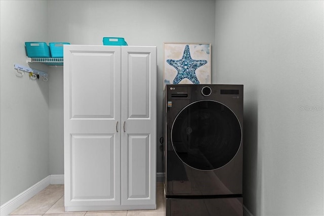 clothes washing area with cabinet space, baseboards, washer / dryer, and tile patterned flooring
