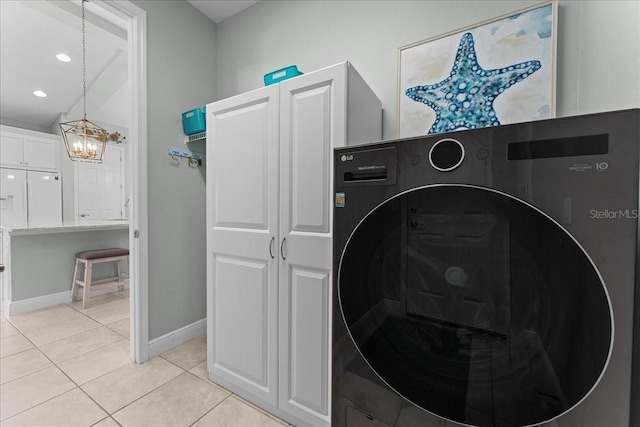 laundry room featuring light tile patterned flooring, baseboards, washer / clothes dryer, a chandelier, and cabinet space