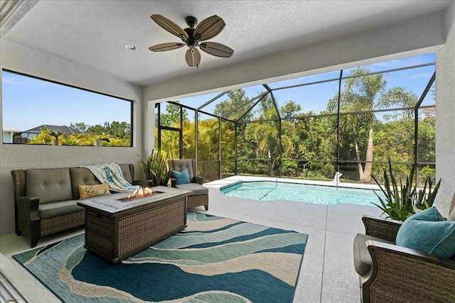 pool featuring an outdoor living space with a fire pit, a patio, a ceiling fan, and glass enclosure