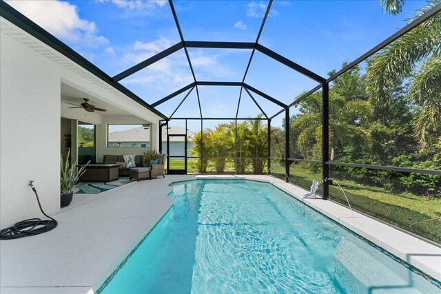 outdoor pool with glass enclosure, ceiling fan, an outdoor living space, and a patio area