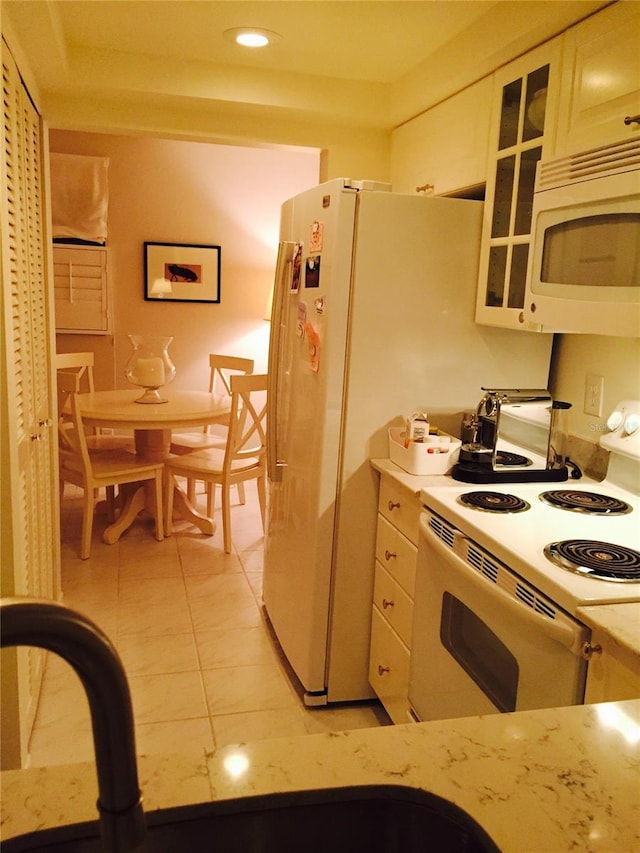 7050 Fairway Bend Ln Unit 167, Sarasota, FL 34243 - kitchen with white appliances, glass insert cabinets, light tile patterned floors, white cabinetry, and recessed lighting