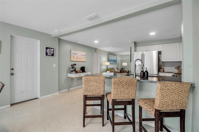 kitchen featuring dark countertops, a breakfast bar area, a peninsula, and visible vents