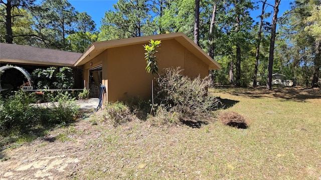 view of side of property featuring a lawn and stucco siding