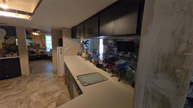 kitchen with light countertops, dark cabinets, and ceiling fan