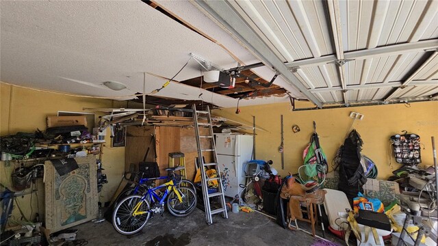 garage with freestanding refrigerator, a garage door opener, and electric panel