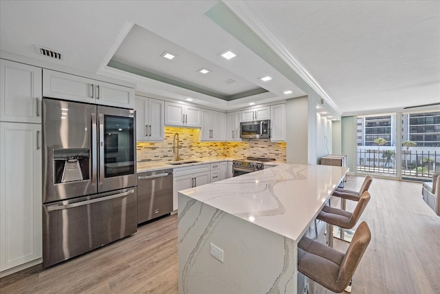 1212 Benjamin Franklin Dr Unit 306, Sarasota, FL 34236 - kitchen with stainless steel appliances, a sink, light wood finished floors, backsplash, and light stone countertops