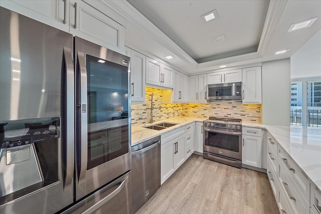 1212 Benjamin Franklin Dr Unit 306, Sarasota, FL 34236 - kitchen featuring appliances with stainless steel finishes, a sink, light stone countertops, light wood finished floors, and white cabinetry