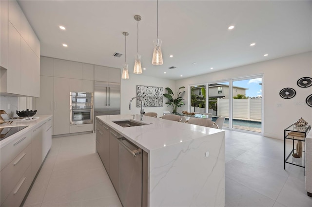 2590 Floyd St, Sarasota, FL 34239 - kitchen featuring modern cabinets, a sink, appliances with stainless steel finishes, a center island with sink, and pendant lighting