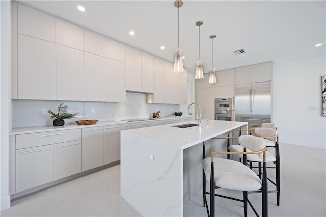 2590 Floyd St, Sarasota, FL 34239 - kitchen with a sink, a breakfast bar, black electric cooktop, decorative light fixtures, and a kitchen island with sink