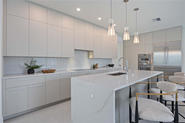 2590 Floyd St, Sarasota, FL 34239 - kitchen with a sink, a kitchen breakfast bar, appliances with stainless steel finishes, decorative backsplash, and hanging light fixtures
