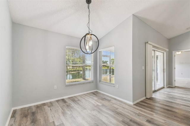 unfurnished dining area with baseboards, vaulted ceiling, and wood finished floors